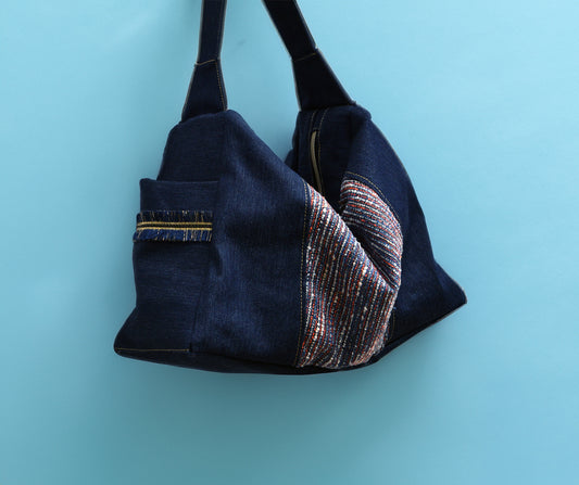 Navy blue handbag with decorative pattern on a light blue background