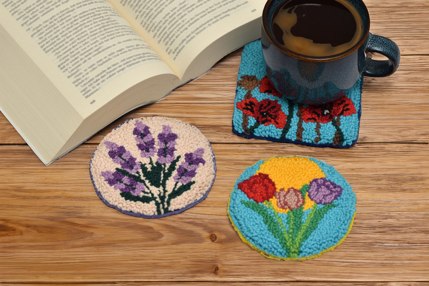 Three floral coasters on a wooden surface with a book and cup of coffee.