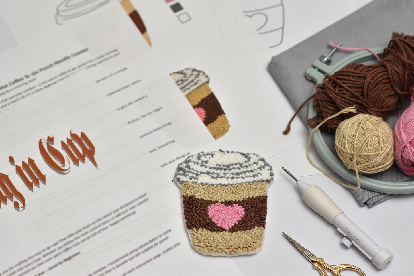 Punch needle coffee cup coaster with yarn and tools on a table