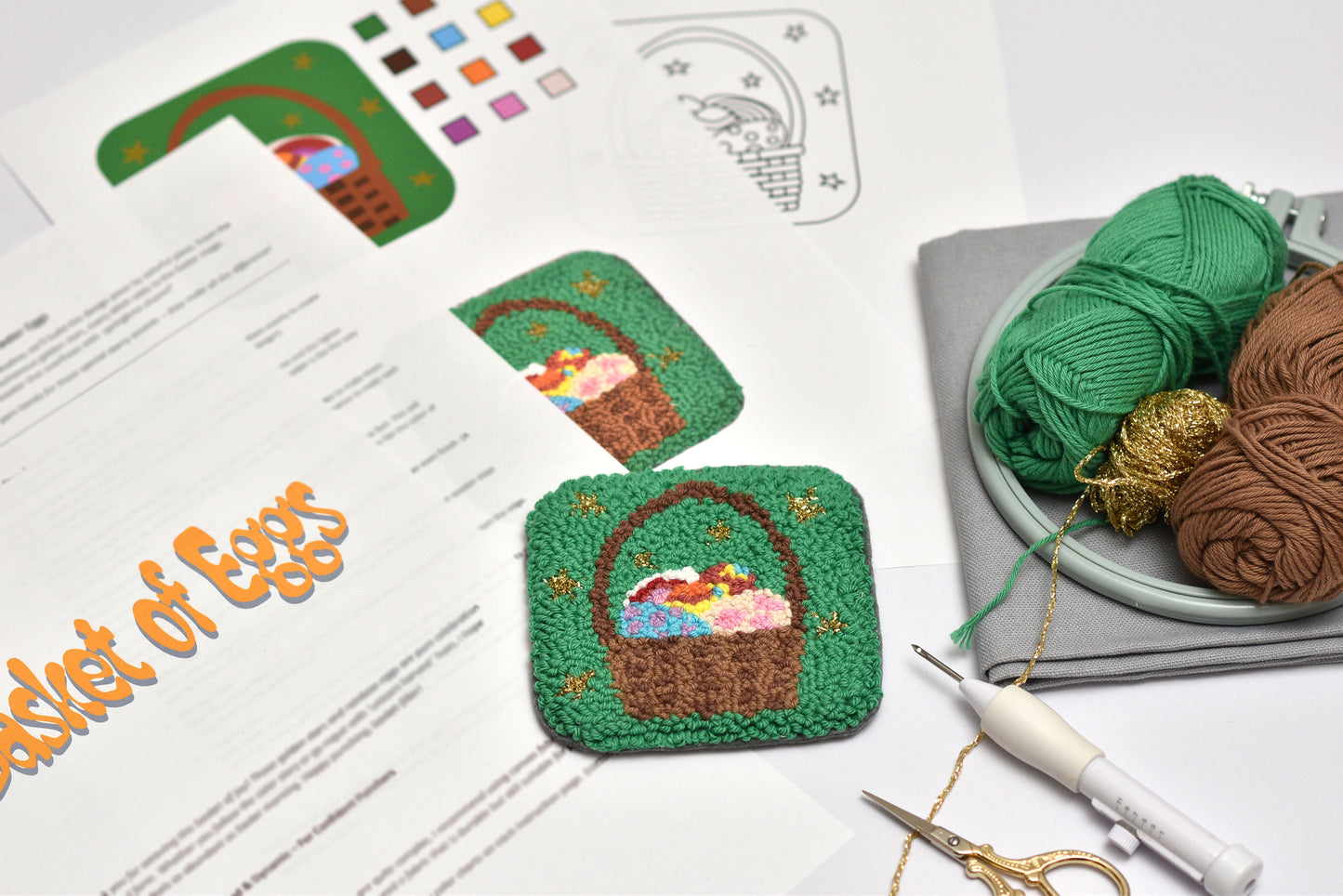 Embroidery hoop with an Easter basket of eggs design, yarn, and embroidery tools on a table.