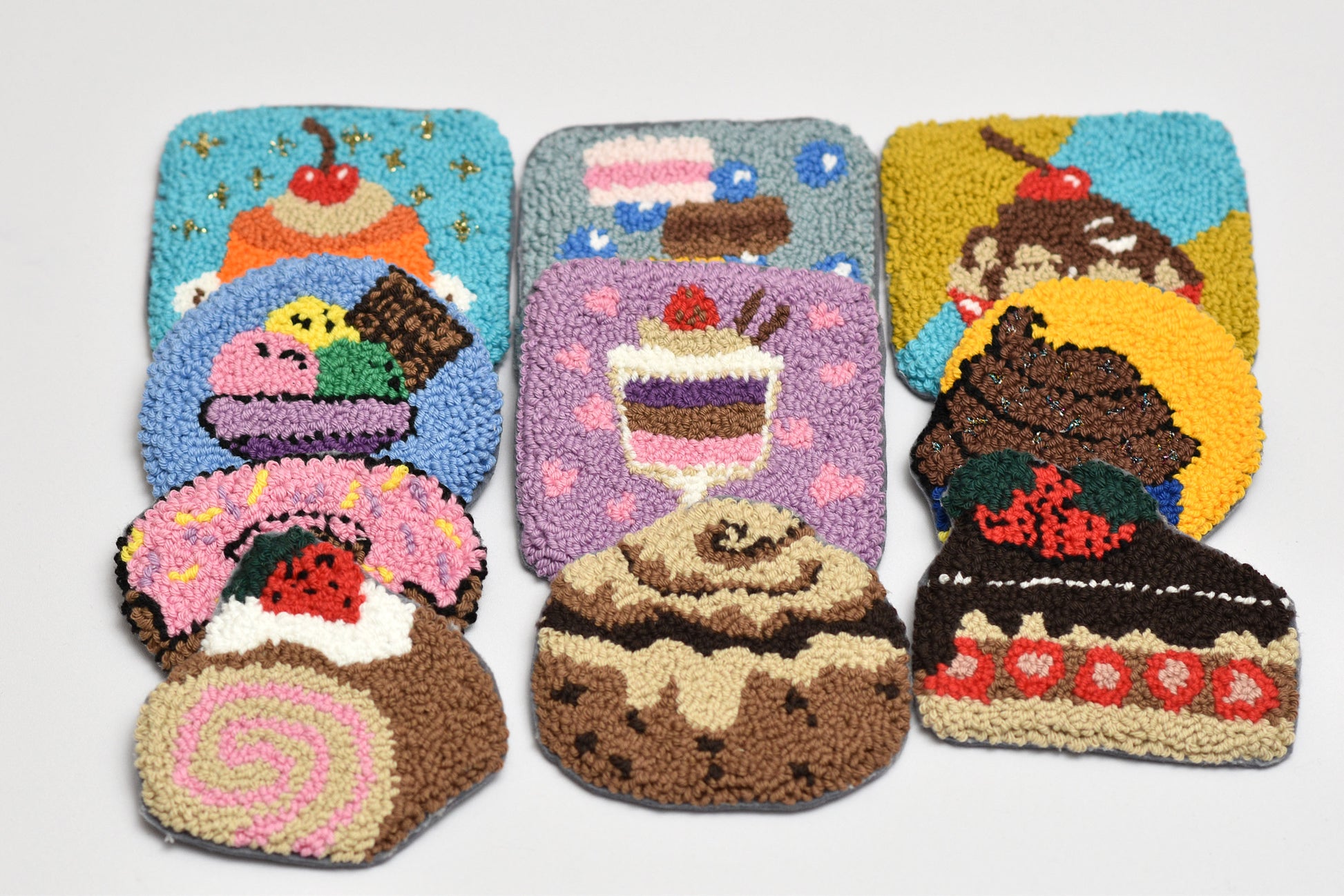 Set of five colorful rug hooks shaped like desserts on a white background