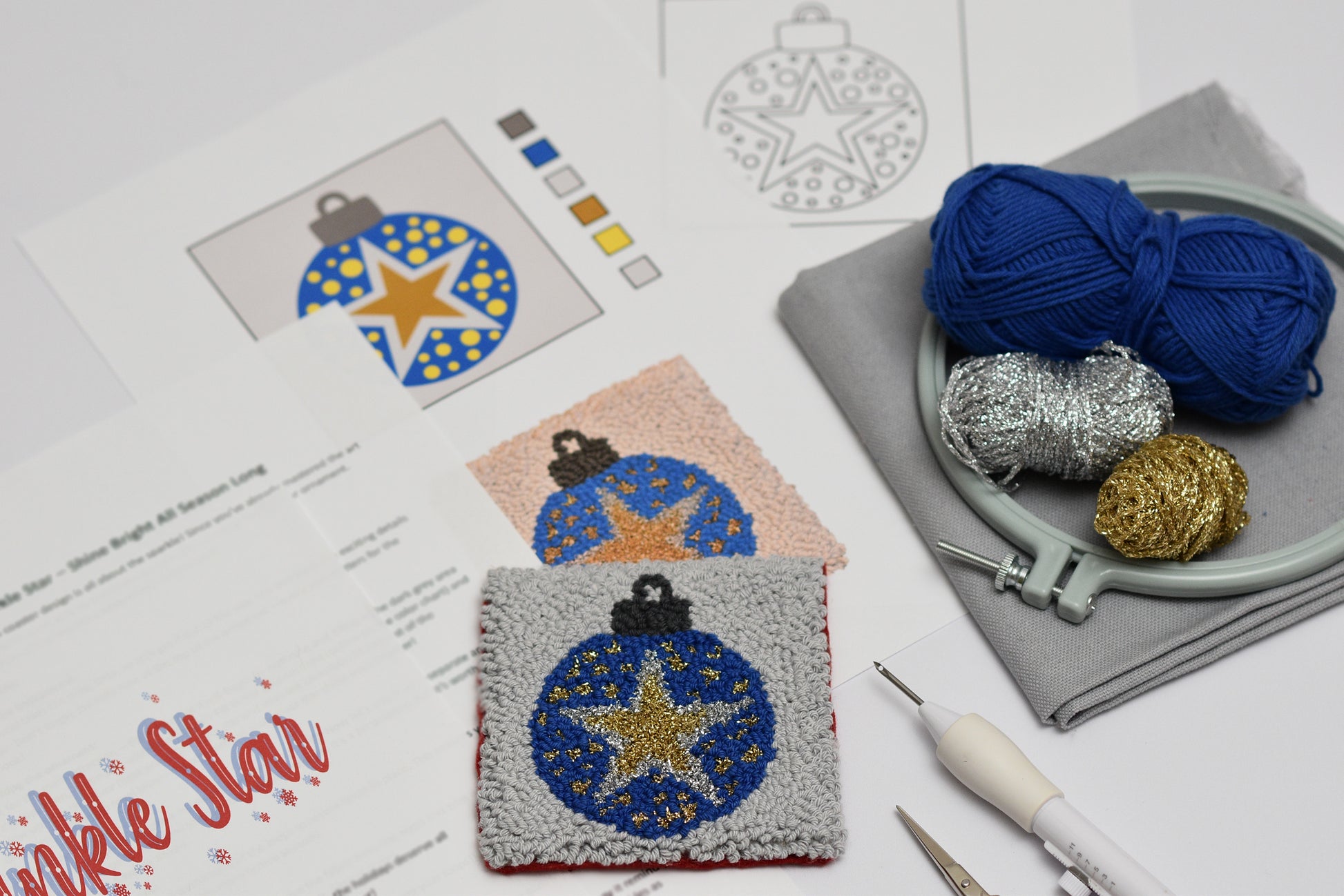 Embroidery hoop with yarn, embroidery design on paper, and embroidered coaster with star pattern.