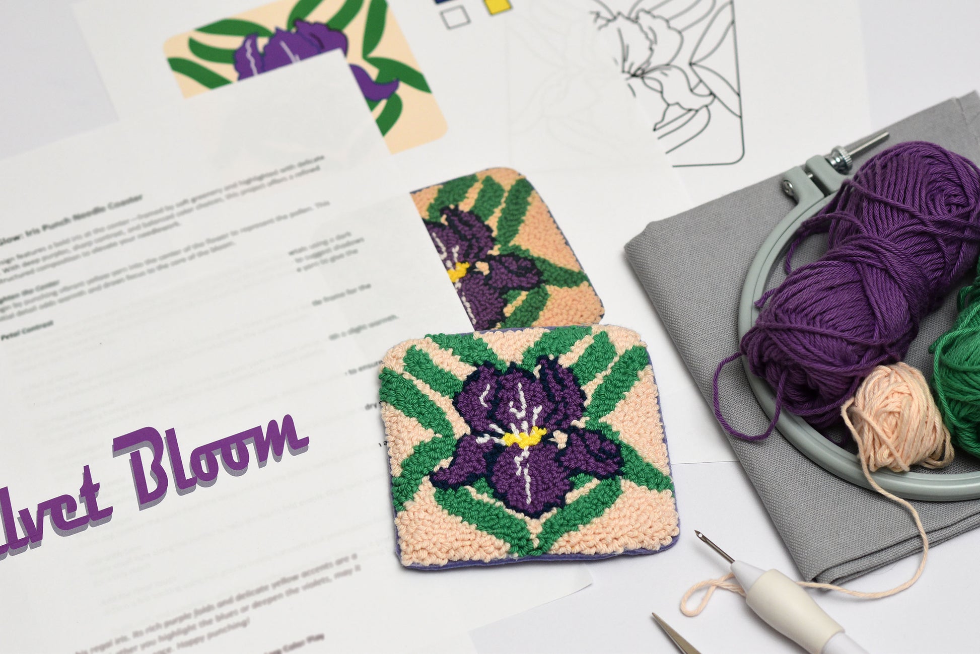 Two embroidered coasters with floral iris designs on a table with yarn and tools.