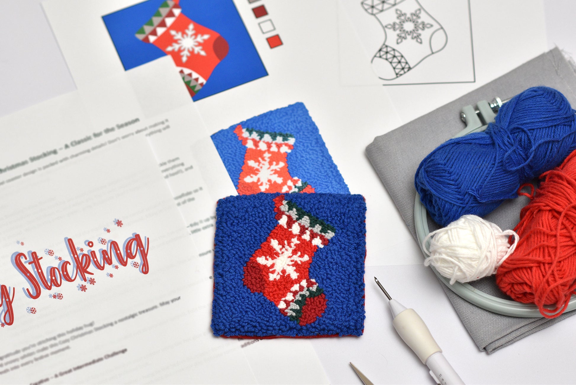 Punch needled stocking coaster pattern with yarn and tools on a table