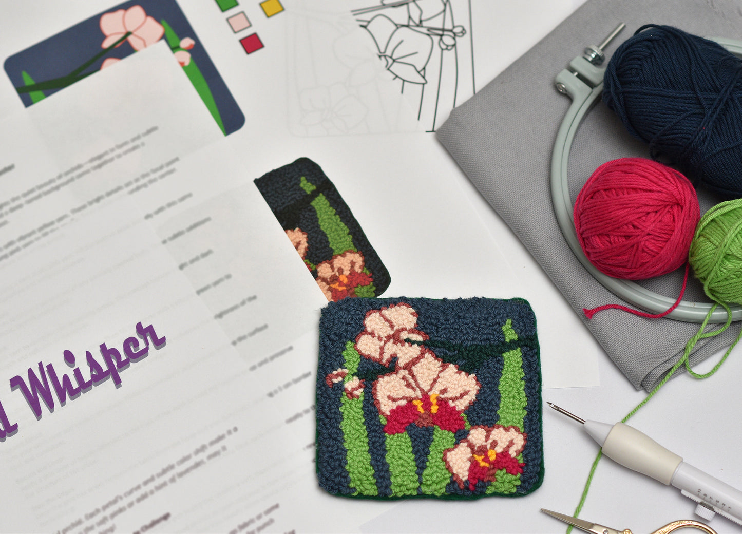 Embroidery coaster with orchid design with colorful yarn, and embroidery tools on a table.