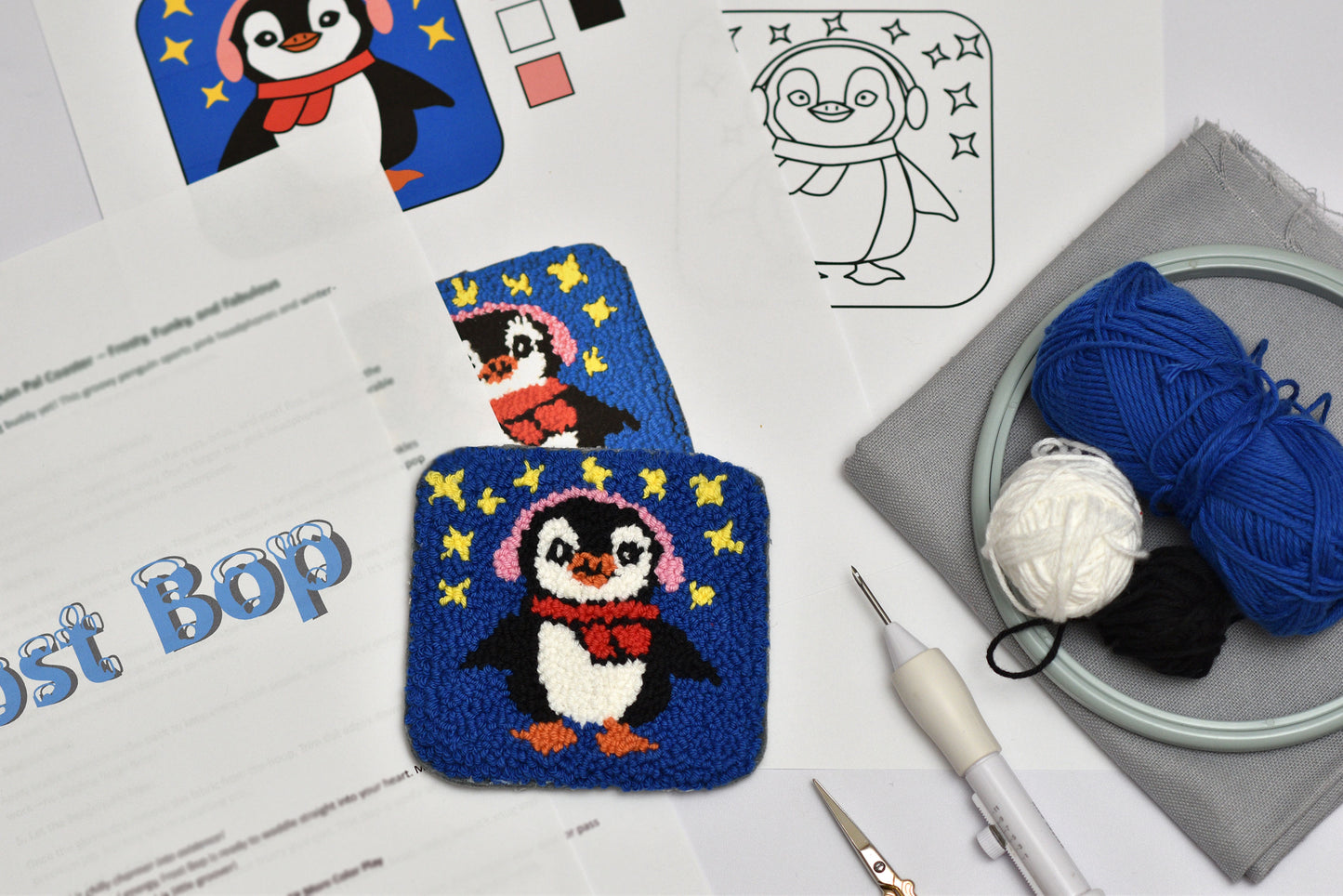 Embroidered penguin coaster with yarn and tools on a table