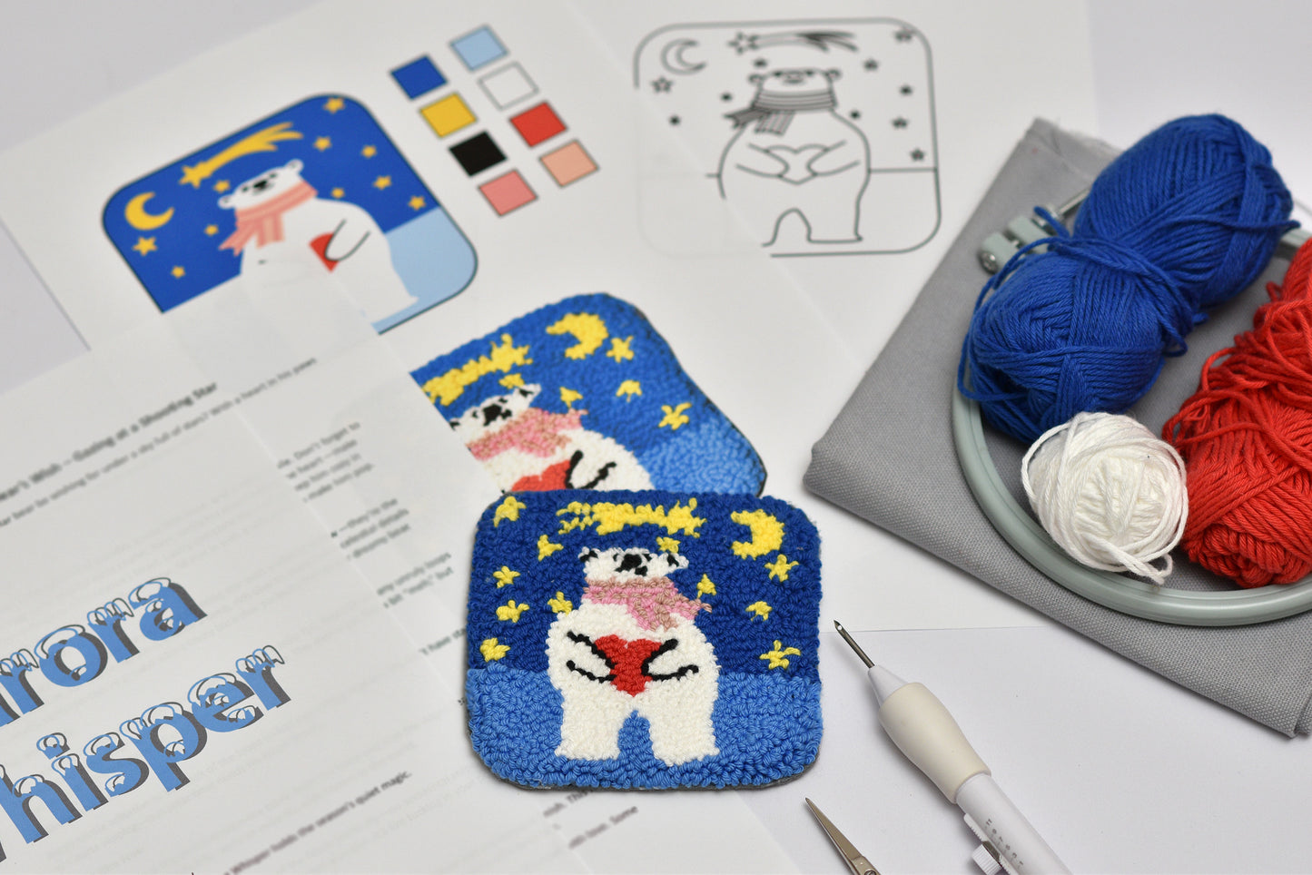 Embroidery coaster project with polar bear character design, yarn, and embroidery tools on a table.