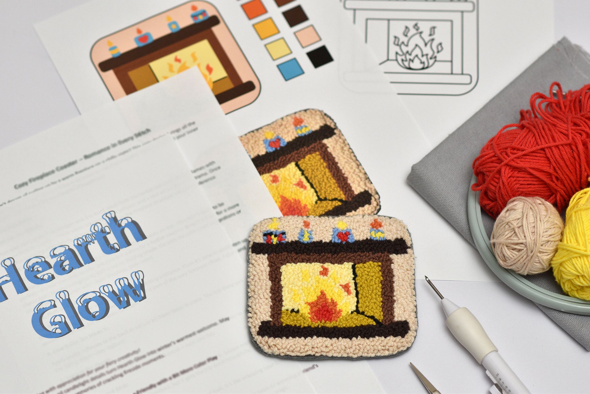 Embroidered coaster resembling a fireplace with yarn and tools on a table