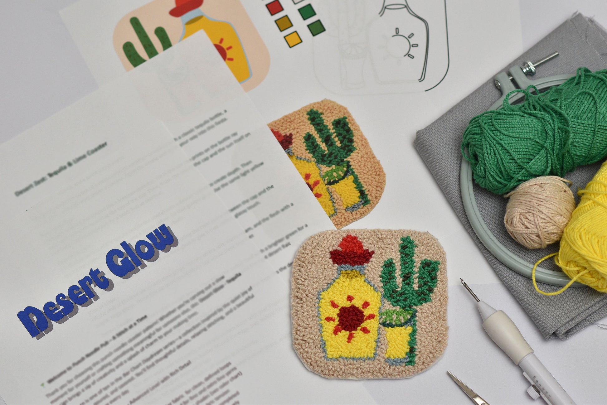 Embroidery coaster project with cactus and Tequila bottle design, yarn, and tools on a table.