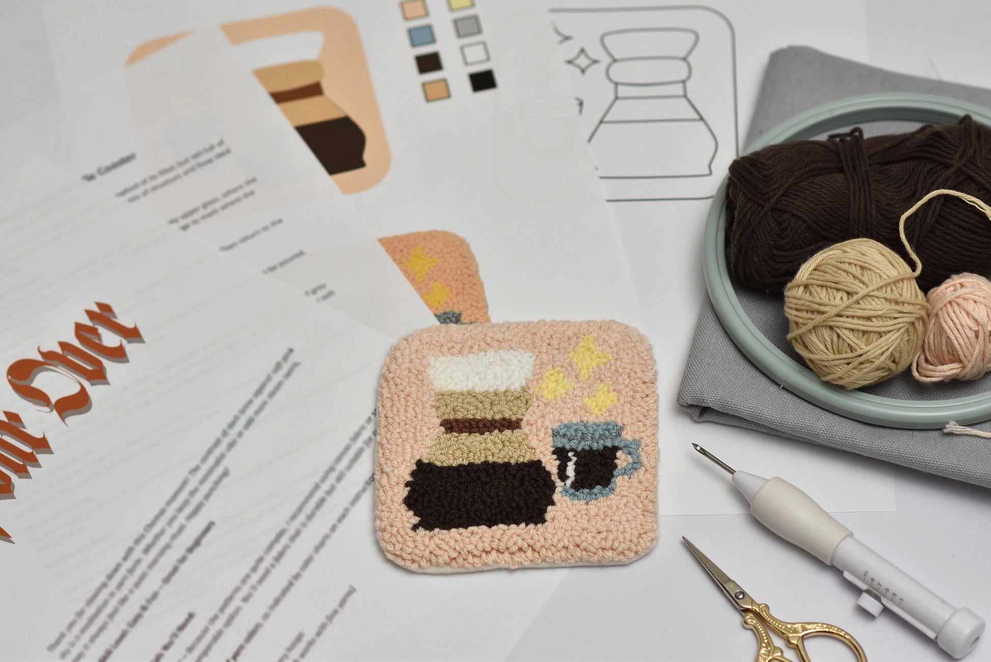 Embroidered coaster with coffee chemex design on a table with yarn and tools