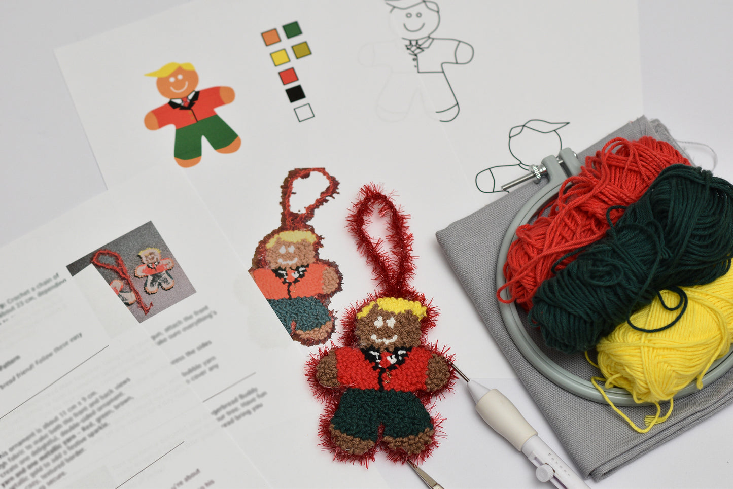 Punch needled gingerbread man ornaments with yarn and patterns on a table