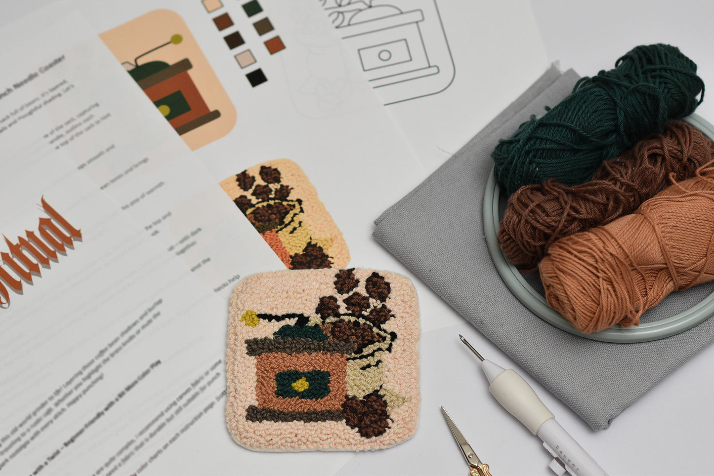 Handmade mug rug punch needle project with yarn and tools on a table with a coffee grinder design