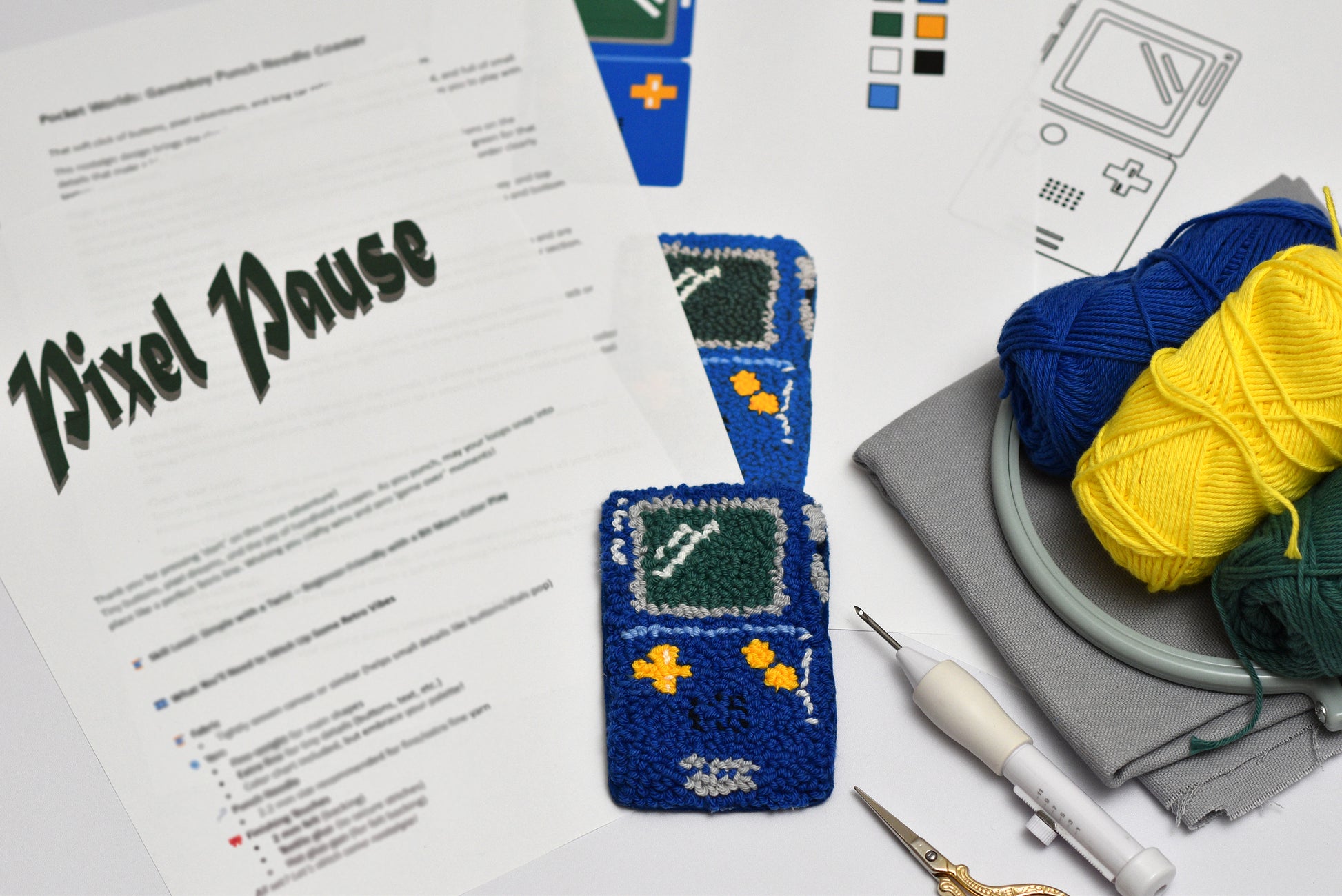 Punch needle game boy designed coaster with yarn and pattern sheet on a white surface
