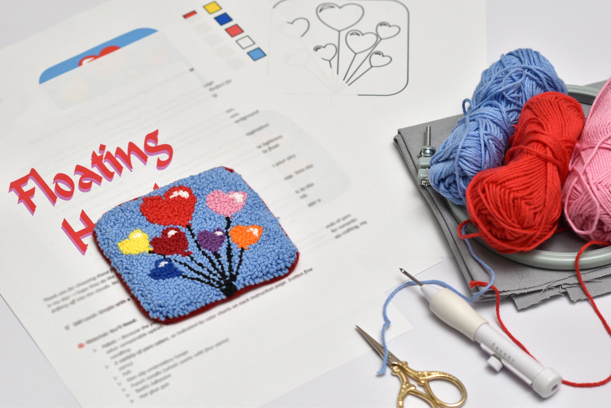 Colorful knitted heart design on paper with yarn, scissors, and a crochet hook.