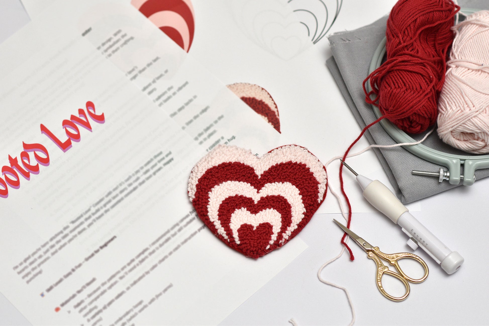 Heart-shaped knitted item with yarn and knitting tools on a table with a 'Notes of Love' card.