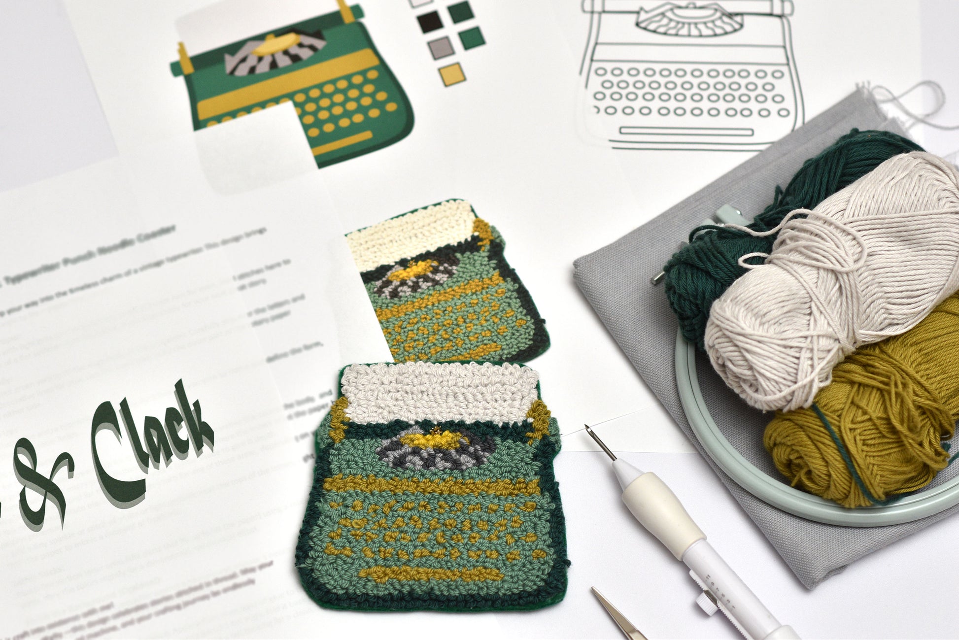 Punch needled coaster with a typewriter design on a table with yarn and knitting tools.