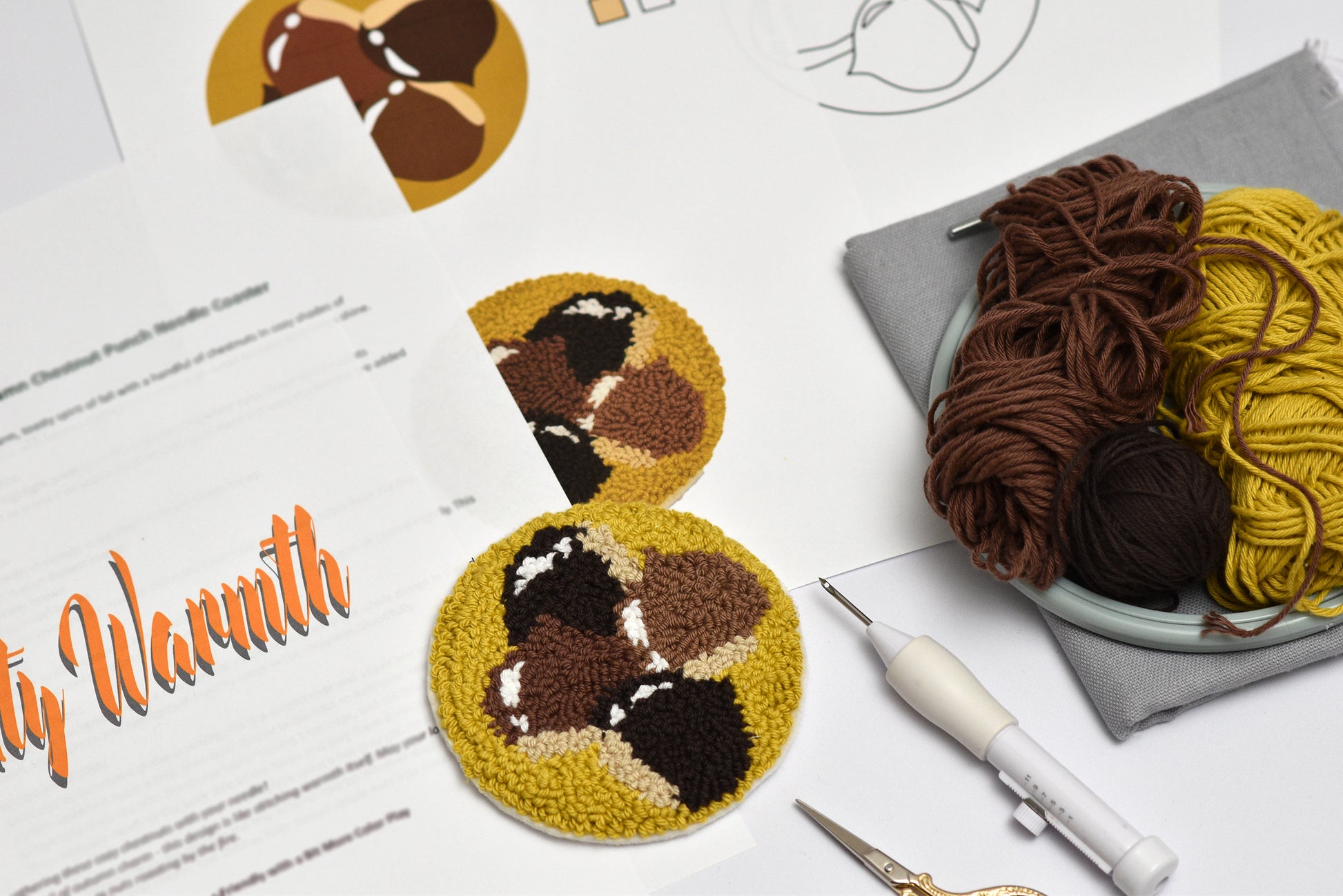 Punch needled chestnut designed coaster with yarn and tools on a table