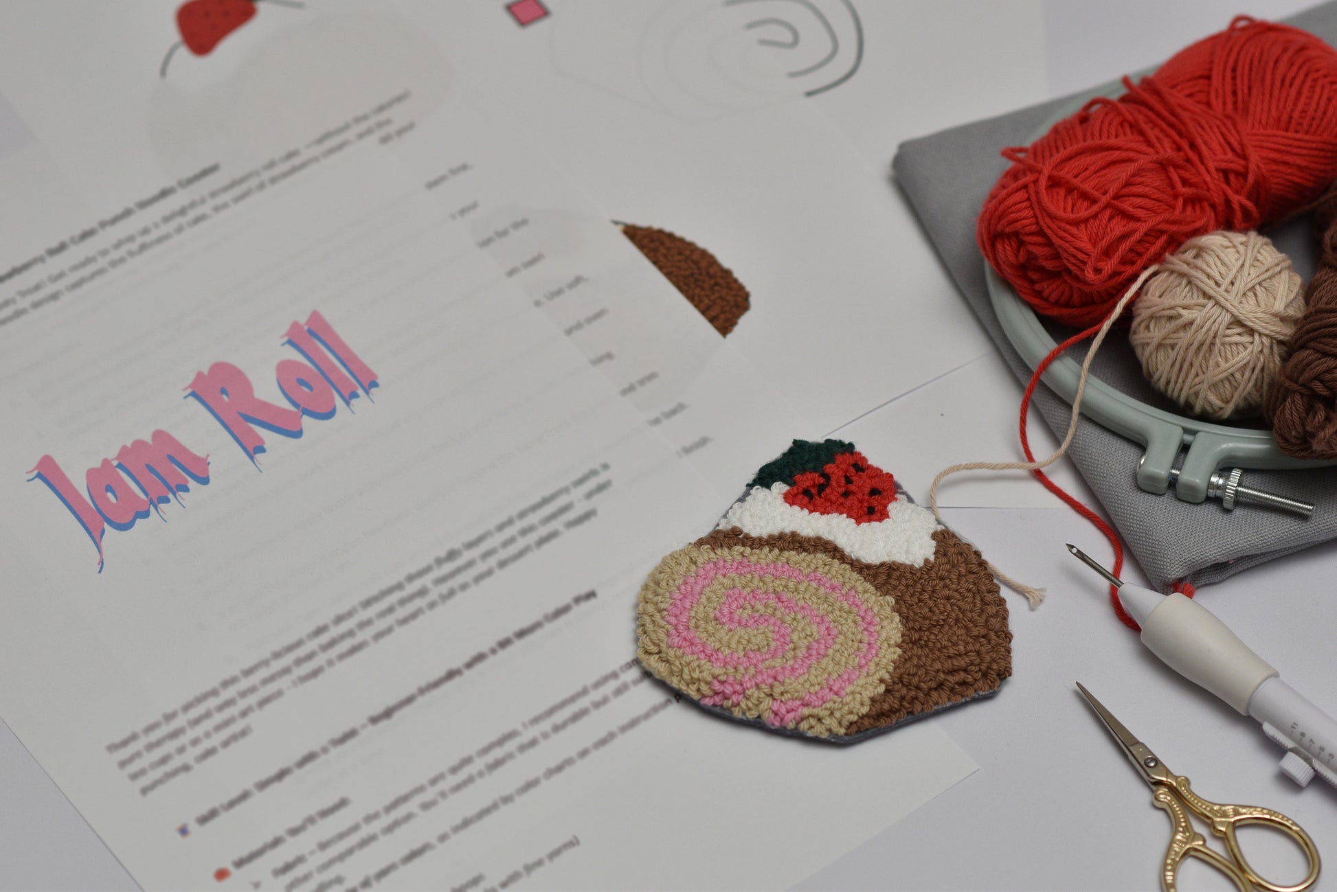 Embroidered cake-shaped coaster on a table with yarn and tools