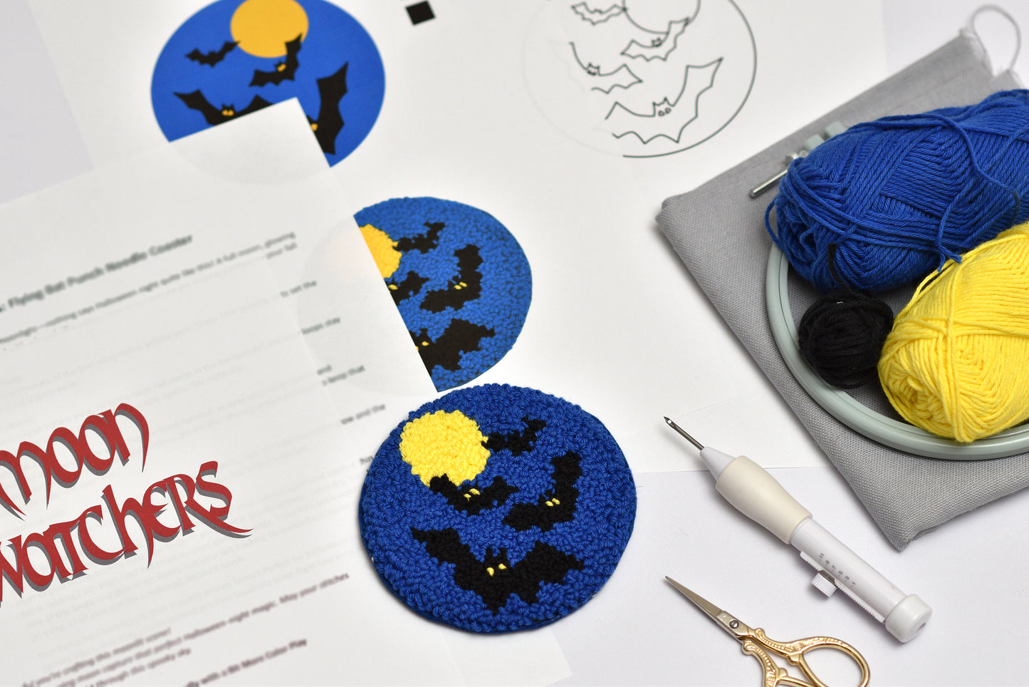 Halloween-themed punch needle coaster project with yarn, scissors, and a pattern sheet on a white surface.