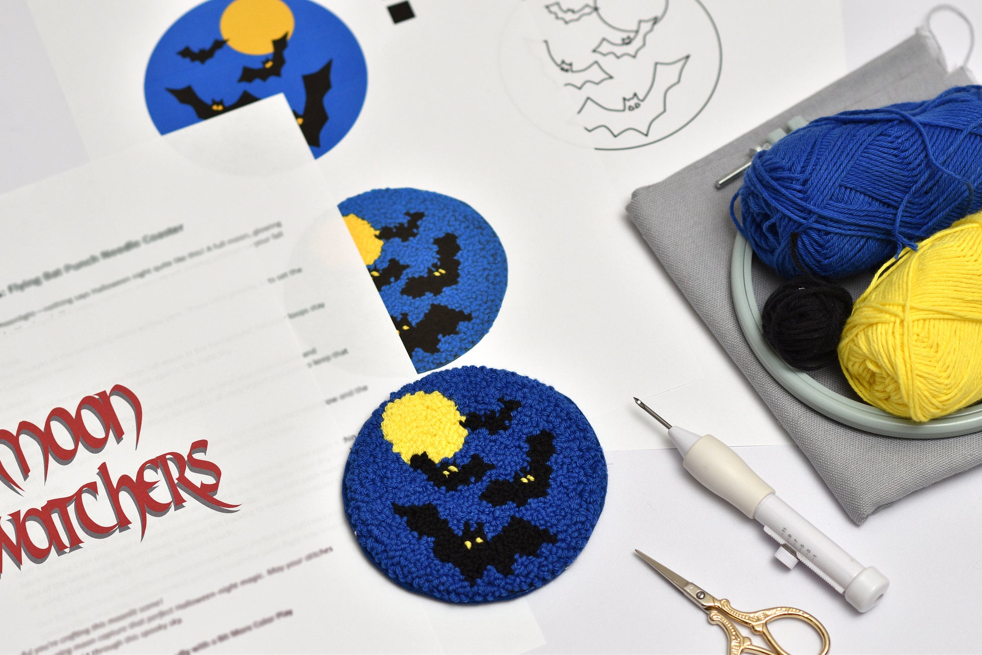 Halloween-themed punch needle coaster project with yarn, scissors, and a pattern sheet on a white surface.