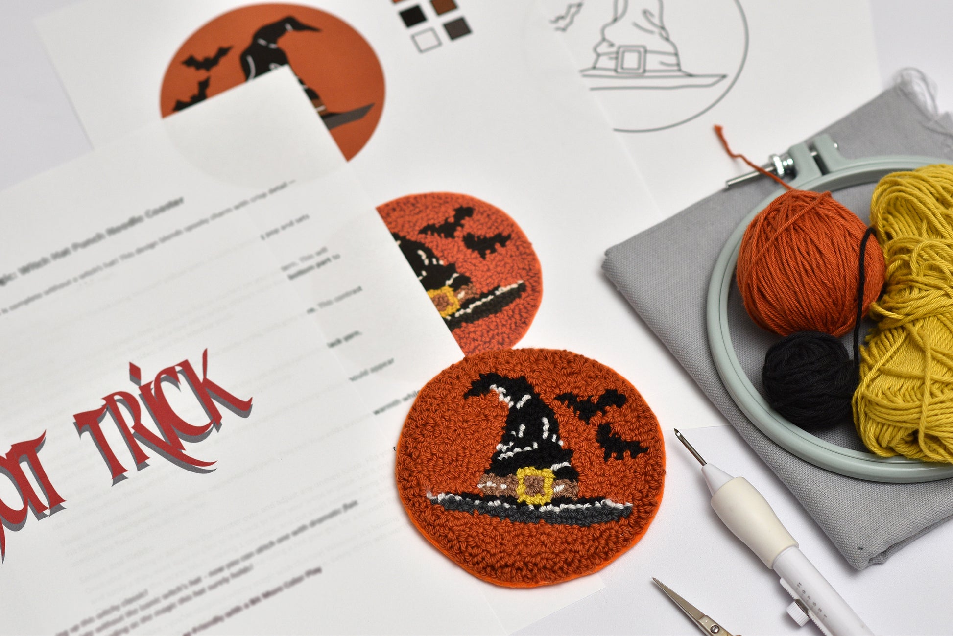 Halloween-themed punch needle coaster project with yarn and tools on a table.