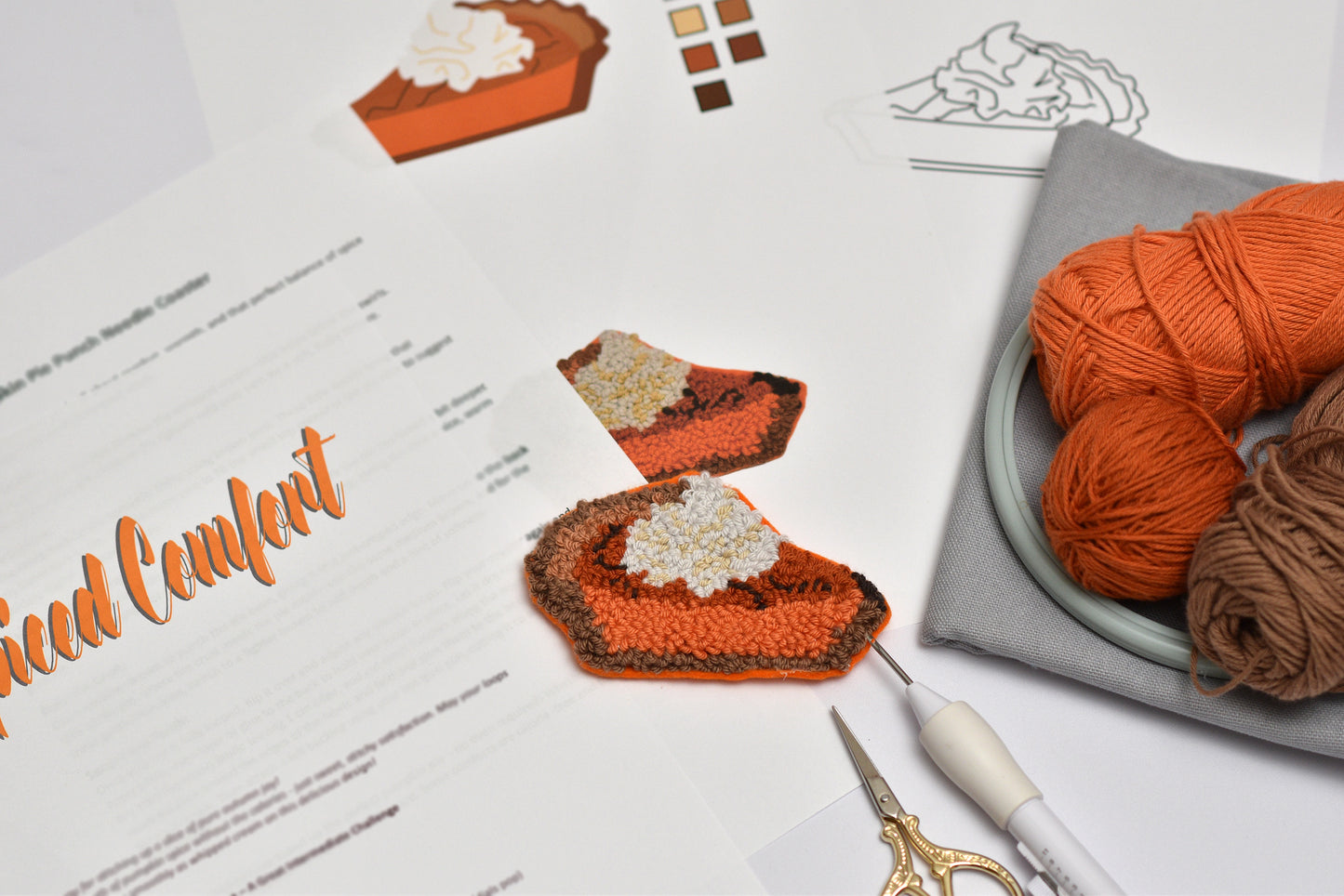 Embroidered pumpkin pie coaster with yarn and pattern sheet on a table