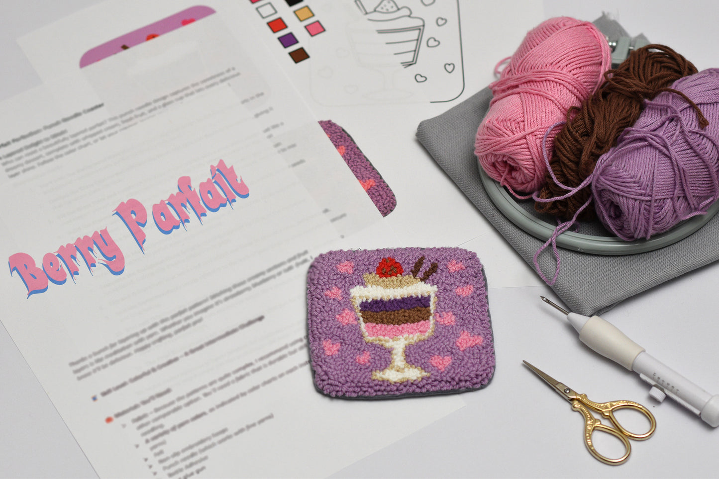 Embroidered dessert coaster with yarn and pattern sheet on a table