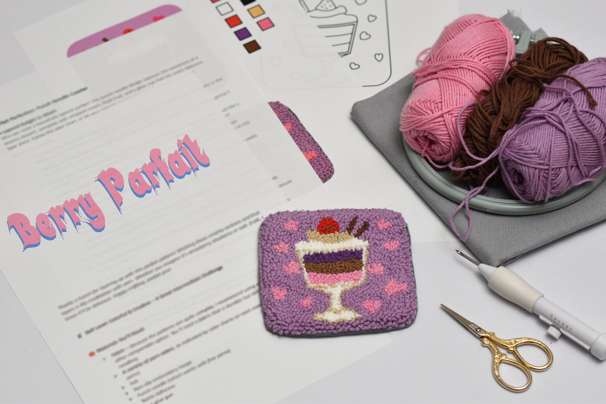 Embroidered dessert coaster with yarn and pattern sheet on a table