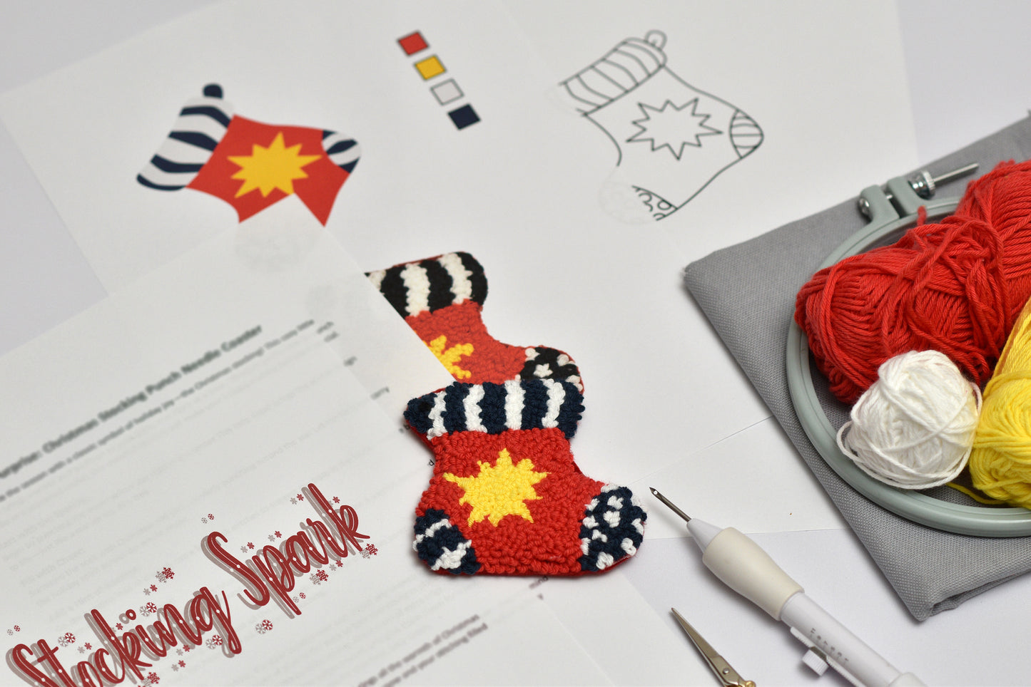 Punch needle stocking shaped coaster with red and yellow design on a table with yarn and knitting tools.