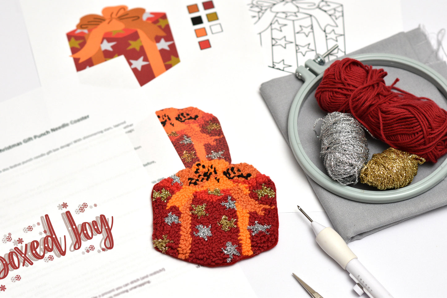 Punch needled gift box coaster with embroidery hoop and yarn on a white surface