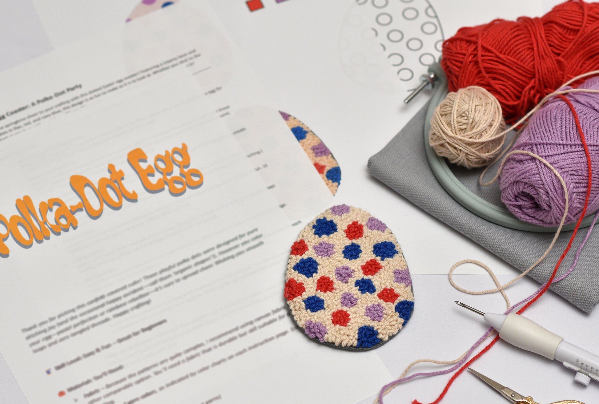 Colorful punch needled Easter egg with yarn and tools on a table
