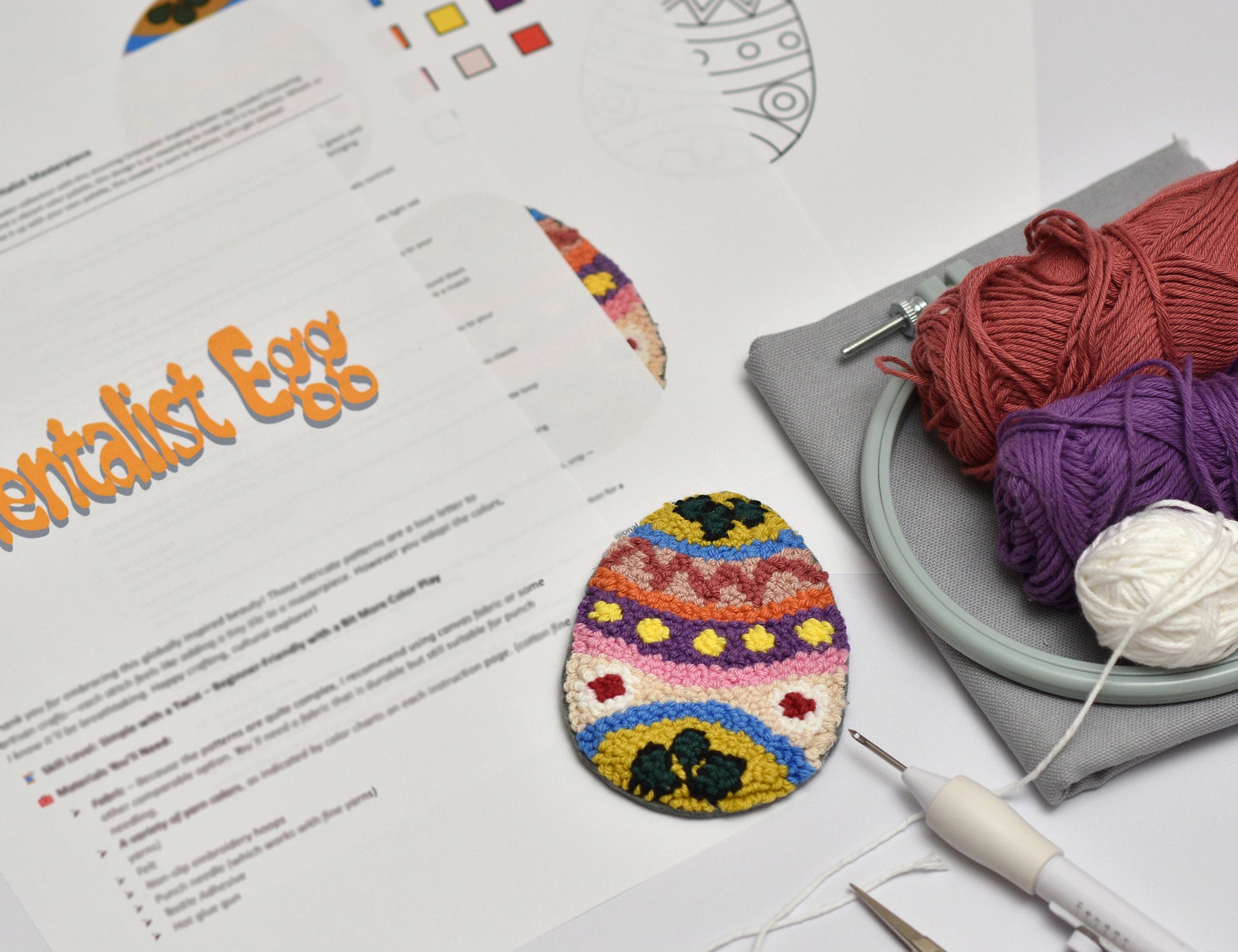 Colorful embroidered Easter egg on a table with yarn and knitting tools.