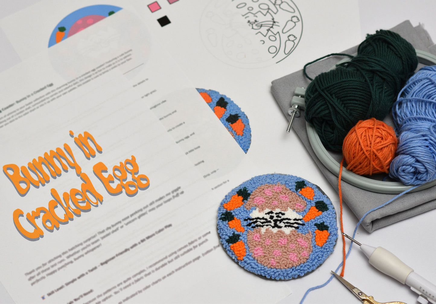 Embroidery coaster project with Easter Bunny design and colorful stitches, yarn, and a pattern sheet on a white surface.