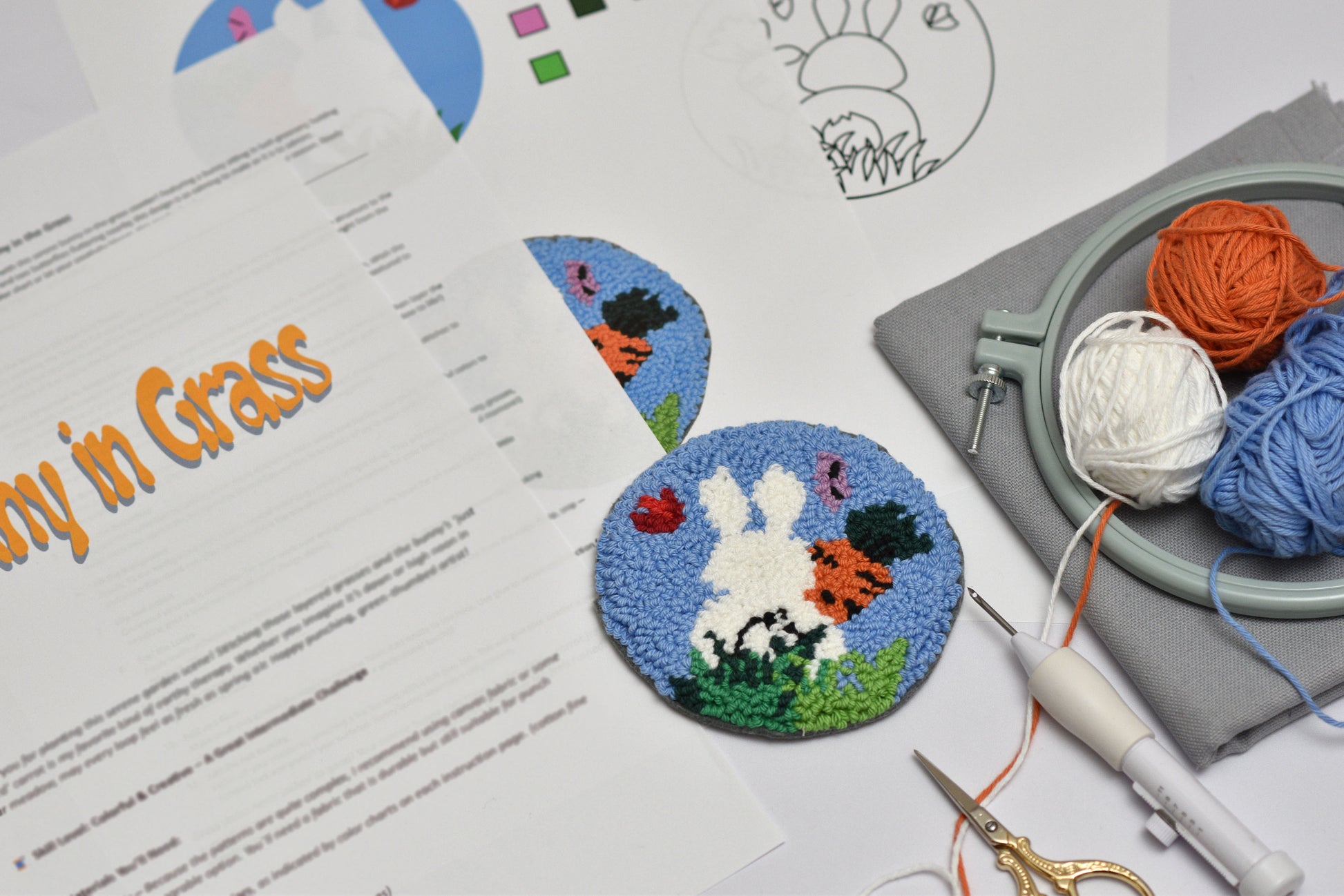 Embroidery hoop with yarn and a completed embroidery coaster with Easter bunny design on a table.