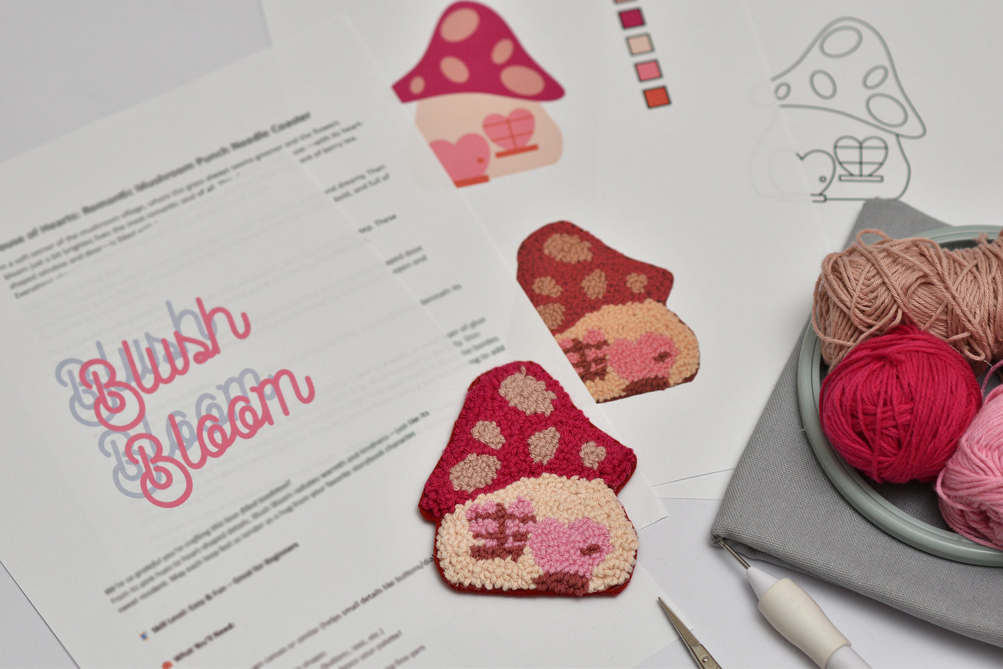 Punch needled mushroom designed coasters on a pattern sheet with yarn and tools.