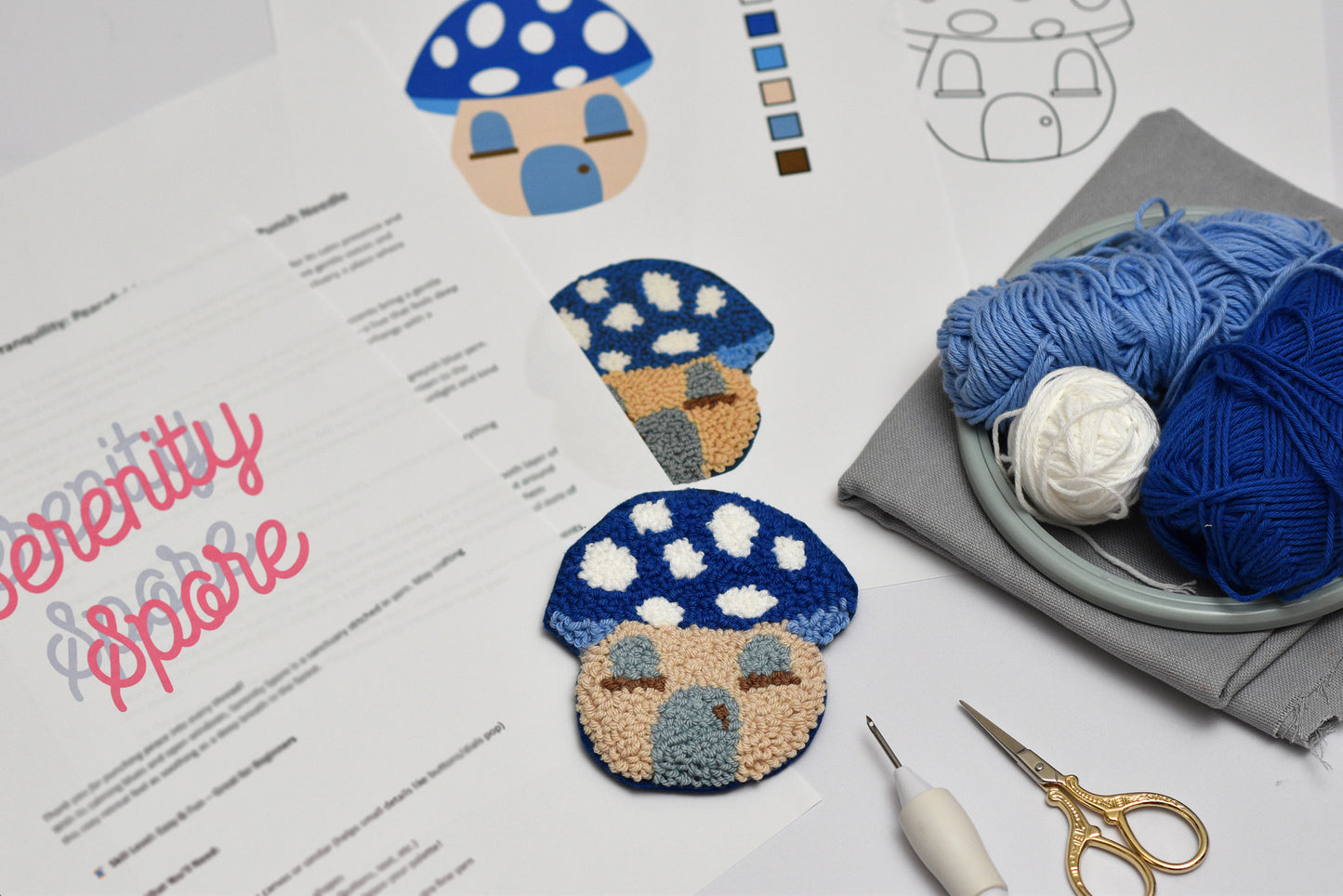 Mushroom-shaped embroidered coasters on a piece of paper with yarn and scissors.