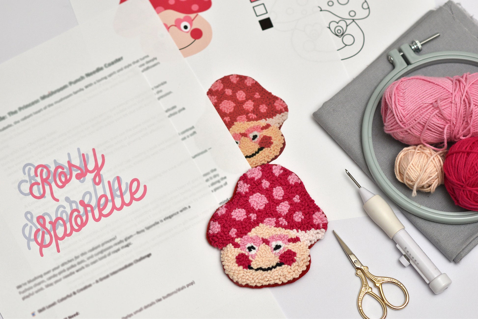 Embroidery coaster project with mushroom-themed coasters, yarn, and sewing tools on a table.