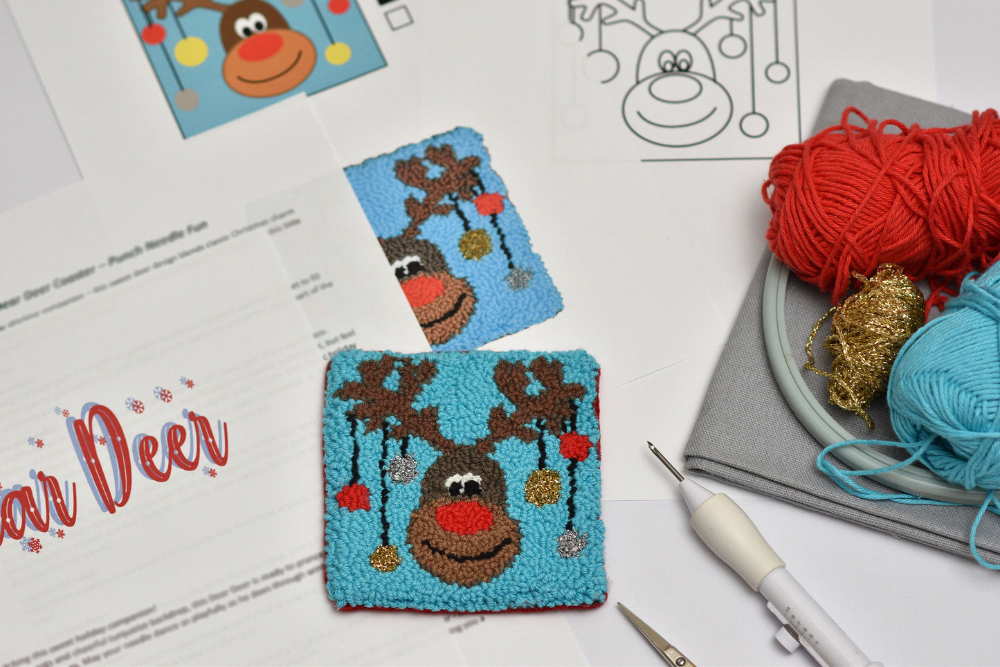 Punch needled reindeer coaster with yarn and knitting tools on a table
