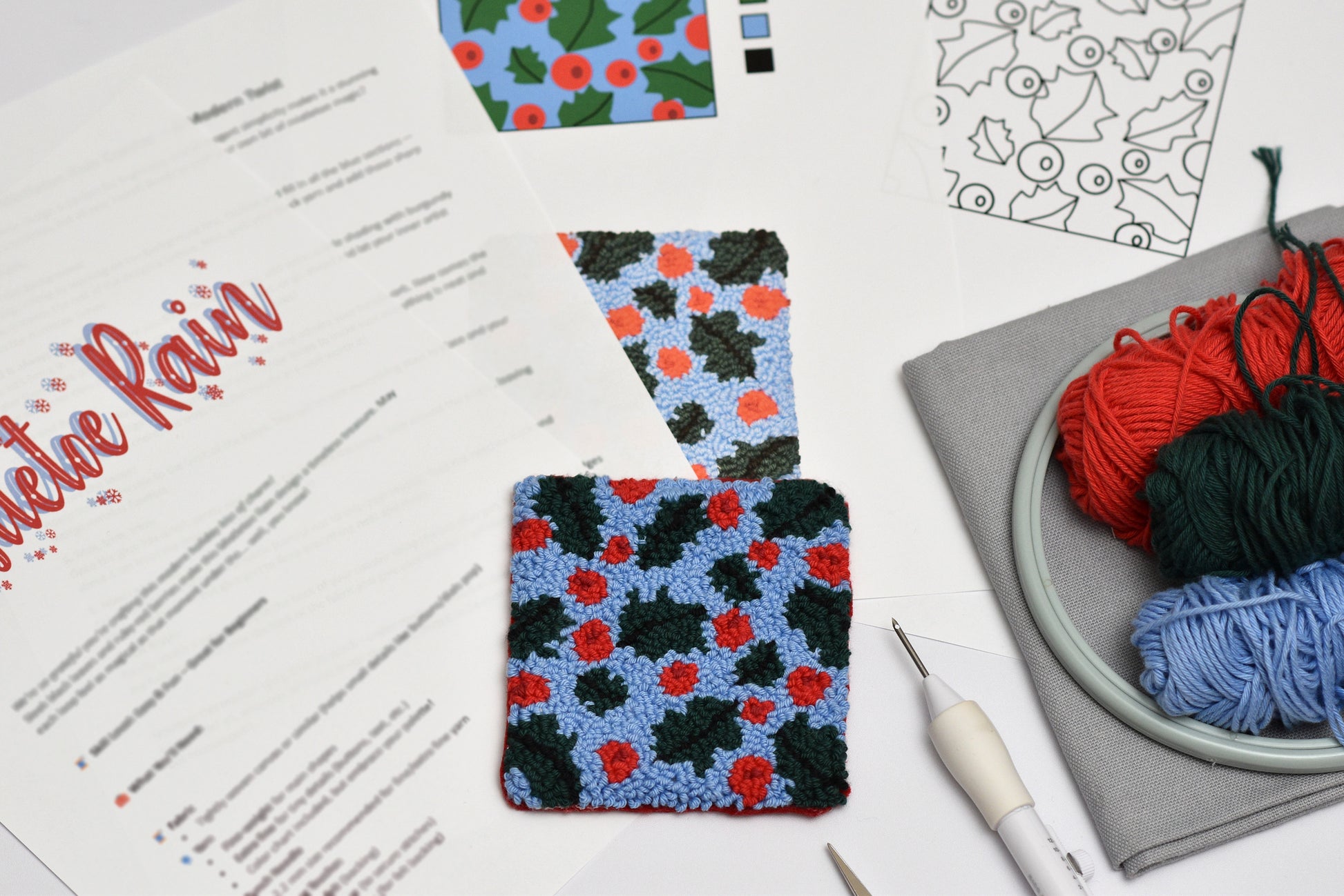 Colorful patterned punch needle coasters with yarn and a pattern sheet on a white surface