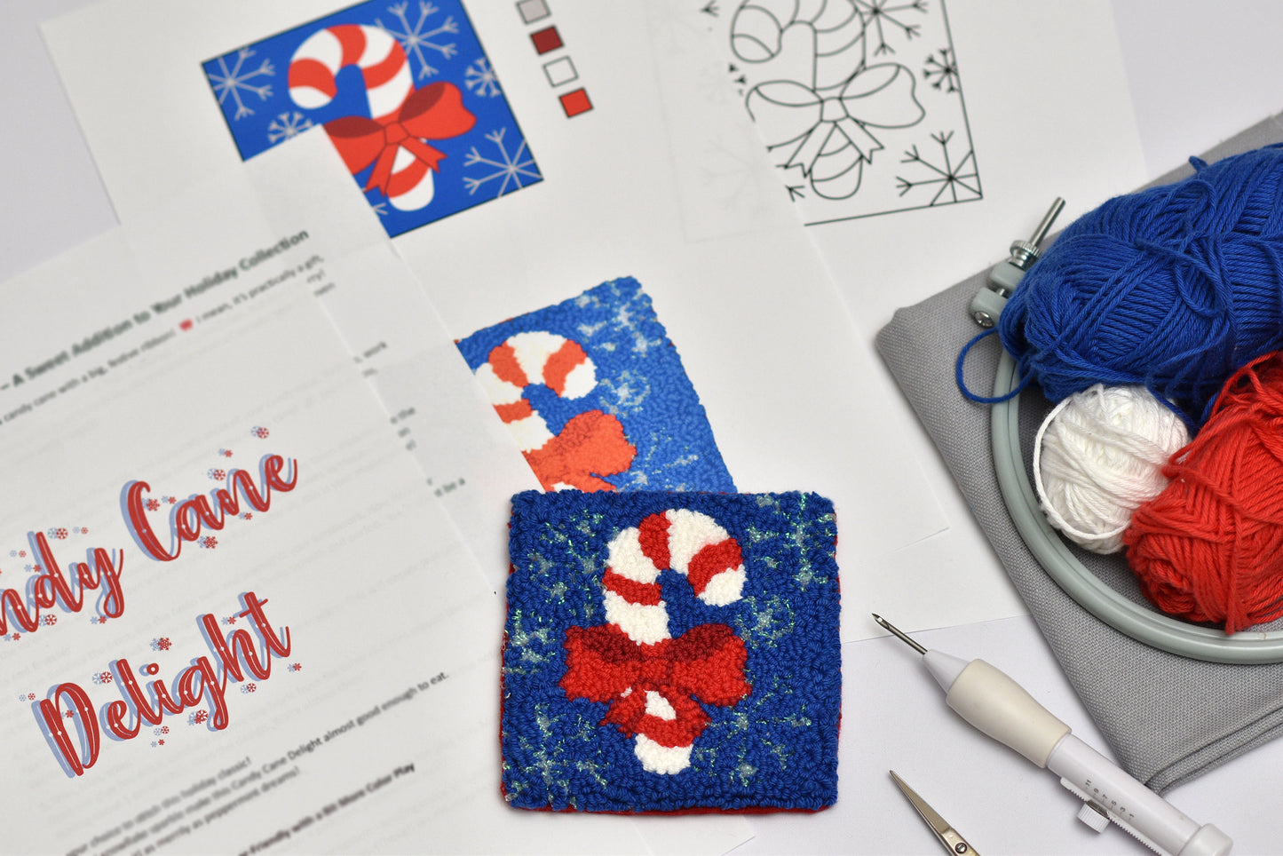 Punch needle coaster with candy cane design on a table with yarn and knitting tools.