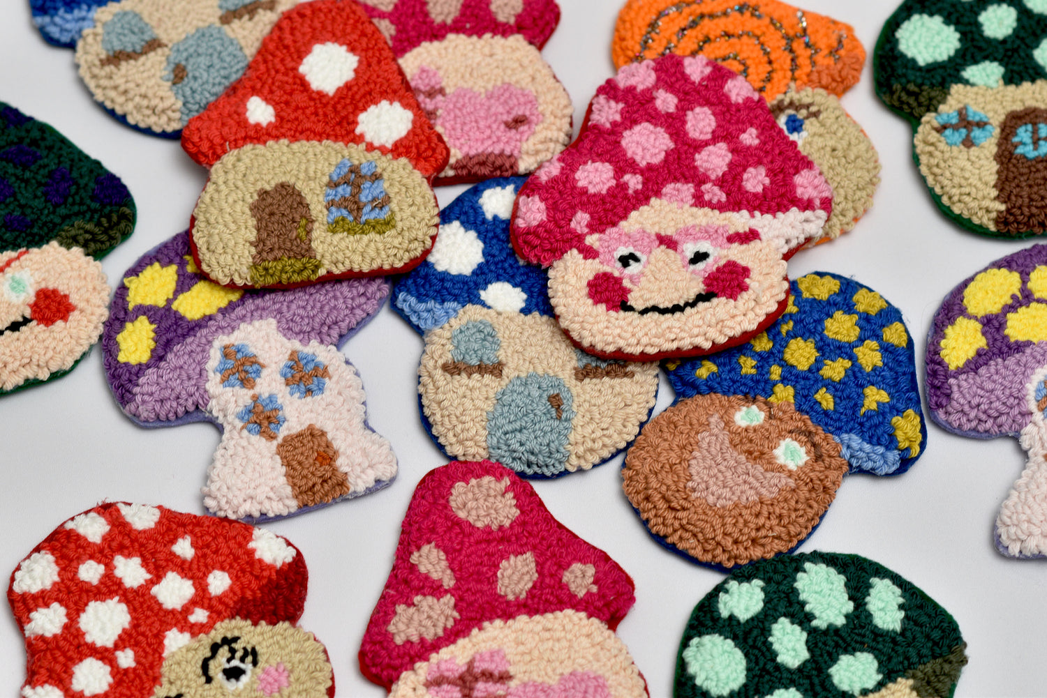 Colorful mushroom-shaped punch needle coasters on a white background