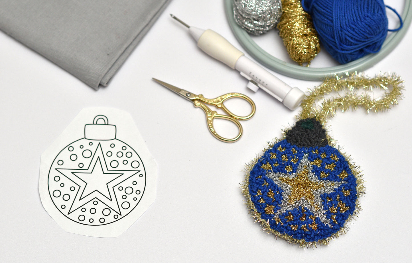 Embroidered ornament with star design next to a template and crafting supplies.