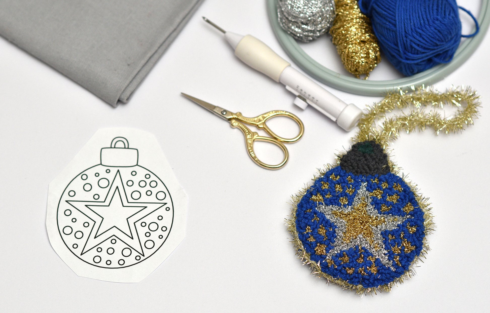 Embroidered ornament with star design next to a template and crafting supplies.