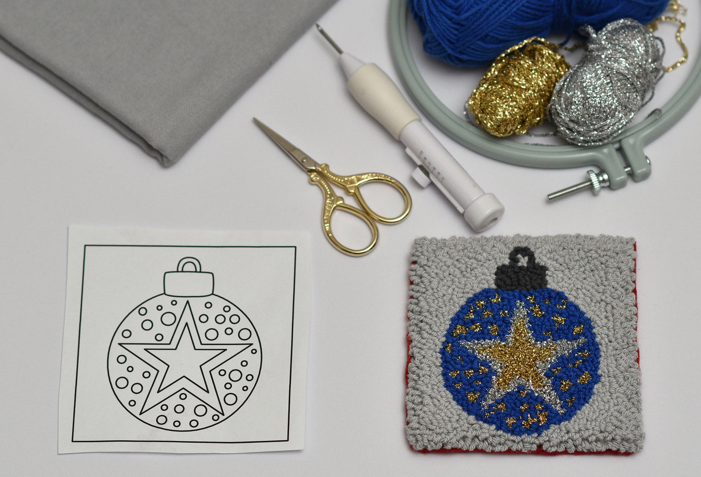 Embroidery coaster project with a star ornament design, scissors, and yarn on a table.