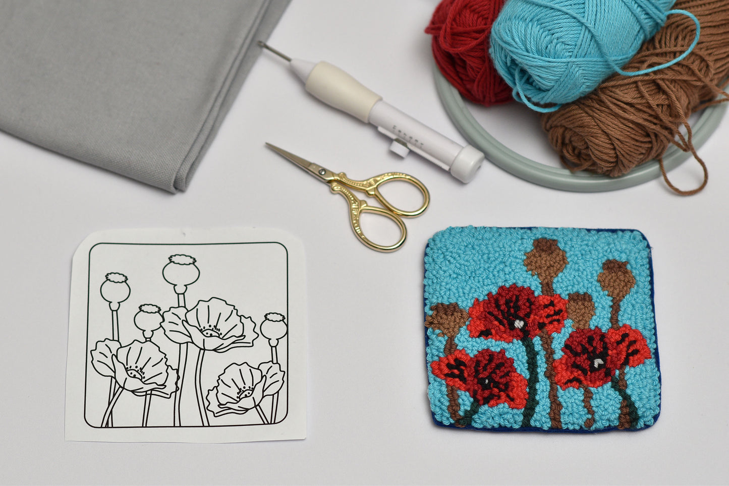 Embroidery hoop with floral design, scissors, and yarn on a table