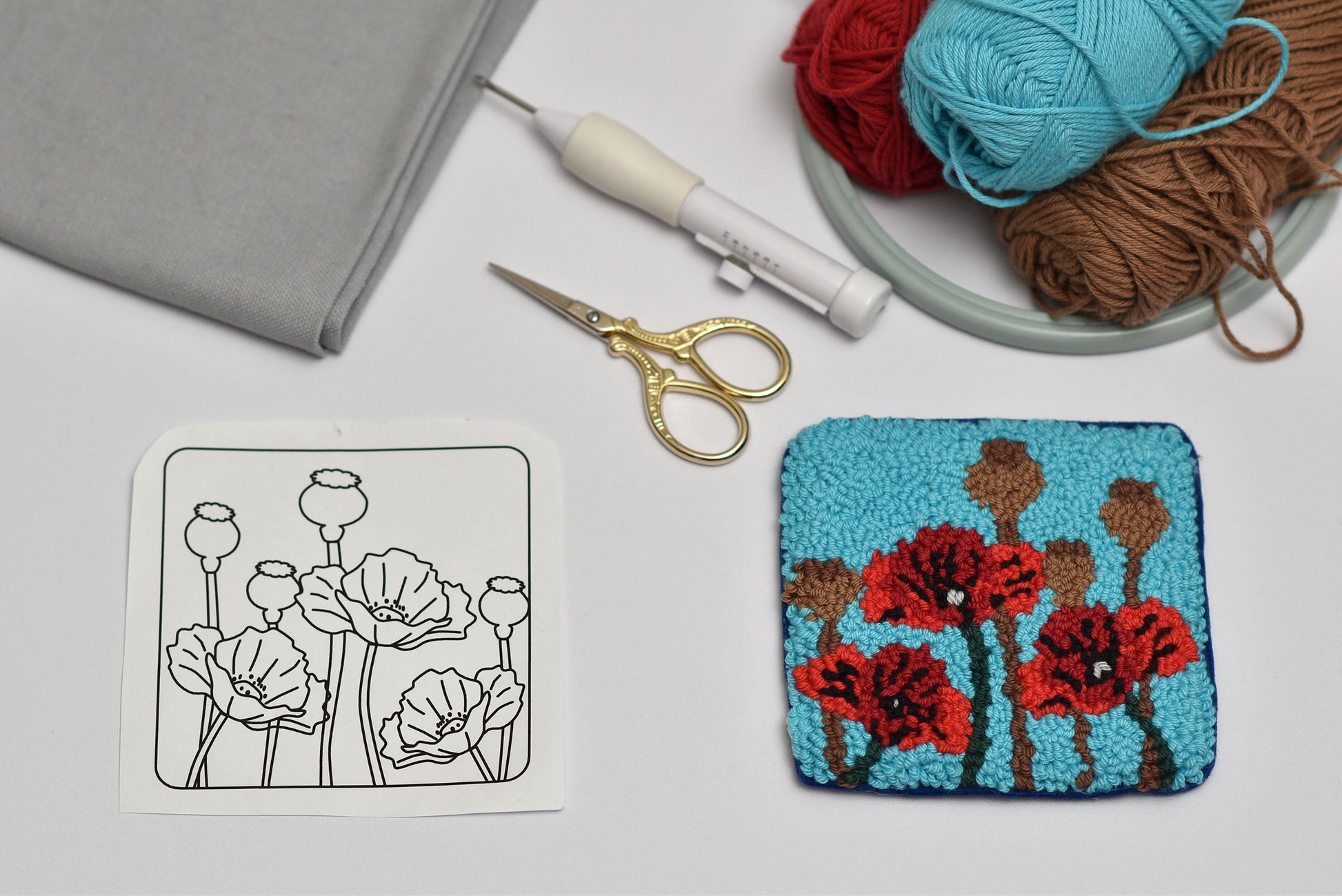 Embroidery hoop with floral design, scissors, and yarn on a table