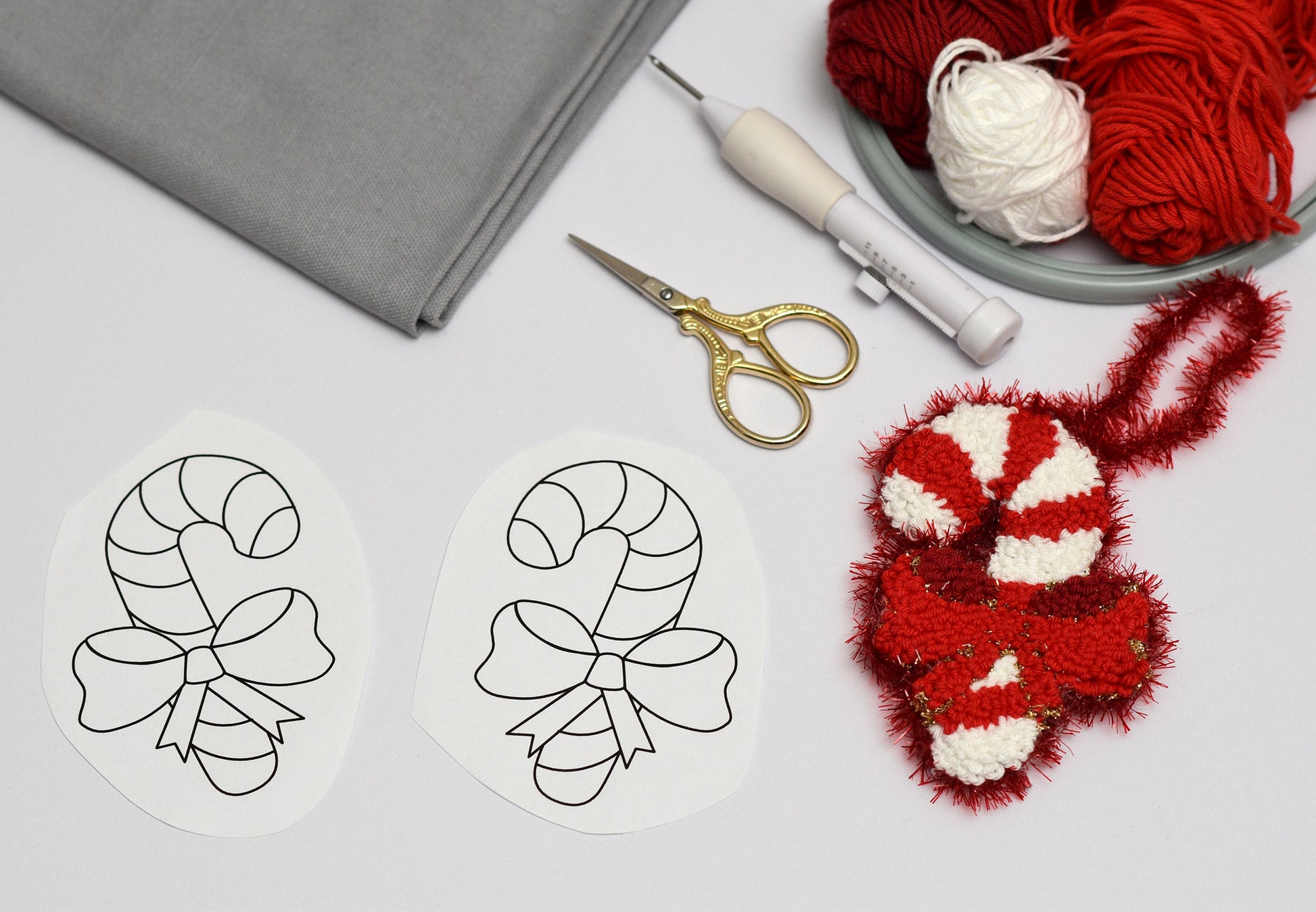 Candy cane design on paper with yarn and scissors on a table