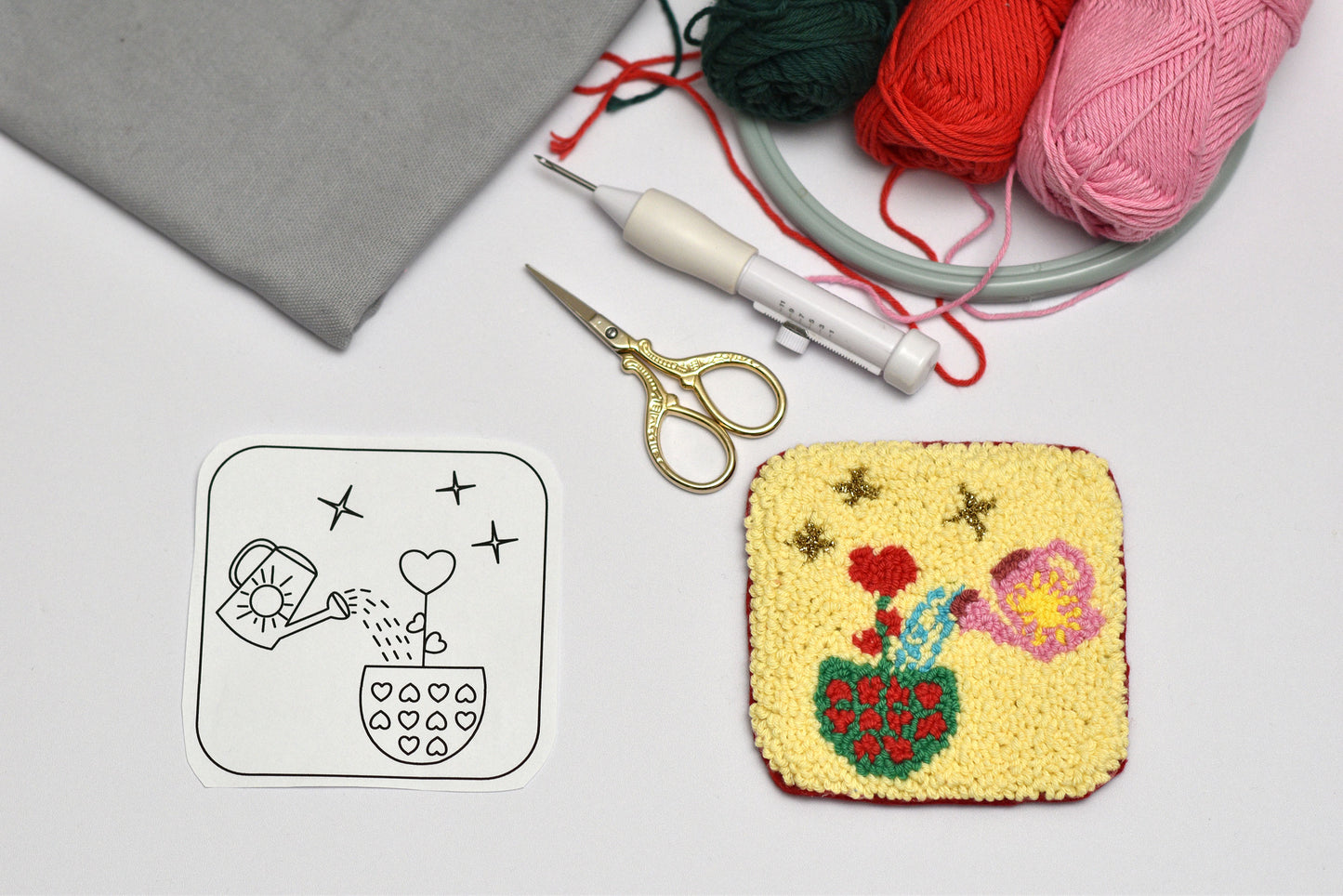 Embroidery hoop with floral design, scissors, and yarn on a light gray background