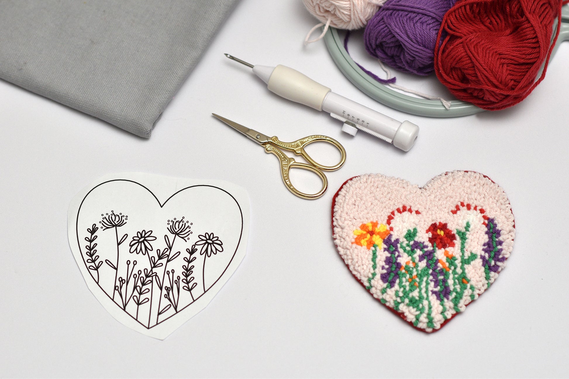 Heart-shaped embroidered design next to a black outline of the same shape on a light gray background.