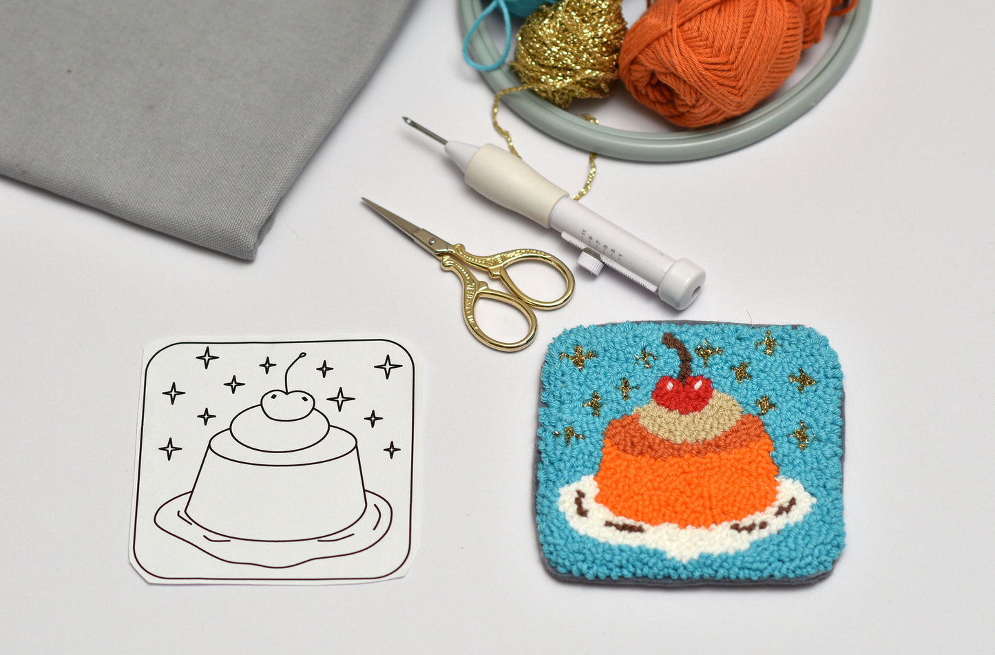 Handmade jelly cake-themed coaster next to a line drawing and yarn on a table.